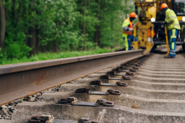 A worker in the process of arailroad track weld repair with a freight train passing