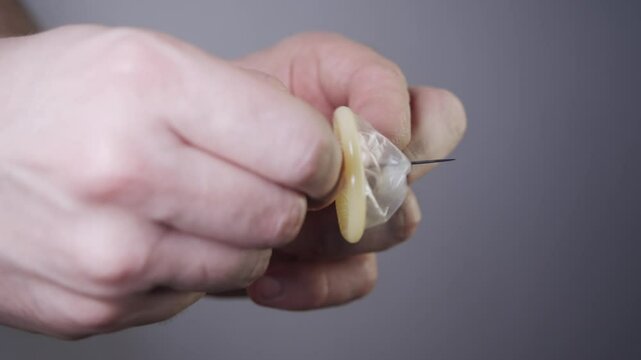 A man pierces a condom with a needle in order to reduce its protective qualities and cause an unplanned pregnancy in a woman.