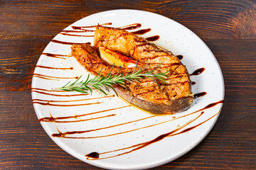 Grilled fish fillet served on a plate with seasoning and garnish