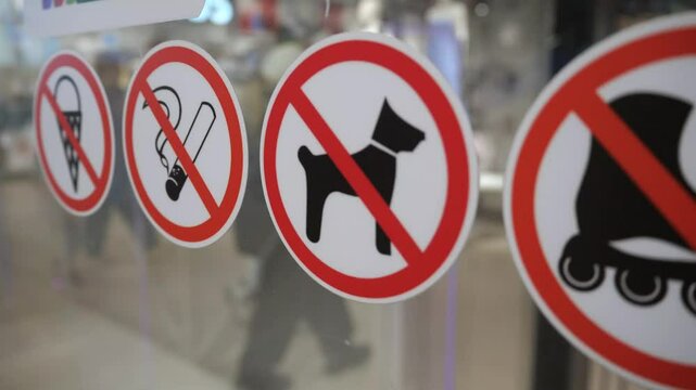 Prohibitory signs on glass - no entry with ice cream, on roller skates, with animals and no smoking sign. Concept - rules of conduct in a public place.