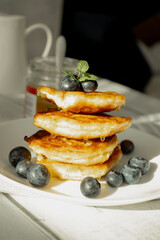 Cottage cheese pancakes with blueberries and sour cream on a white wooden table