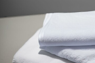 Fototapeta premium A studio photo of a black bathing towel, Fresh fluffy folded towels on grey background, top view. Mockup for design