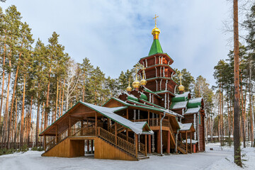 A small wooden church with golden domes and a cross on top of it in Yekaterenburg Russia