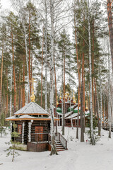 A wooden church with a green roof and a snow covered roof in Ganina Yama Yekaterenburg