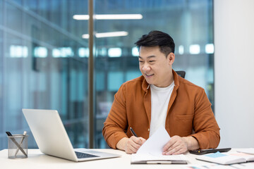 Fototapeta premium A financier is smiling while signing documents during a virtual business conference call in the office