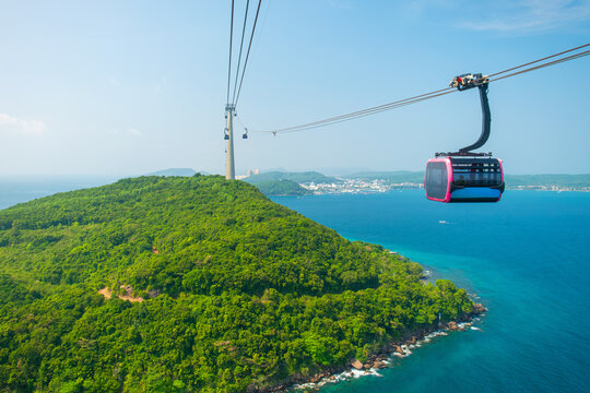 Fototapeta Aerial view of cable car gondola gliding over lush green island hills and turquoise sea. Longest Hon Thom cable car ride in the world on Phu Quoc island, Vietnam. Modern tourism technology
