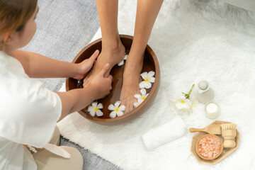 Woman indulges in blissful foot massage at luxurious spa salon while masseur give reflexology therapy in gentle day light ambiance resort or hotel foot spa. Quiescent