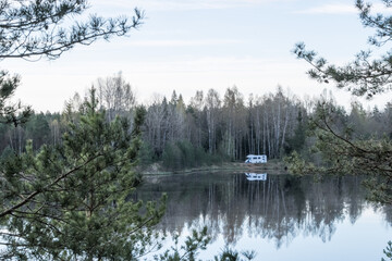 Matsimae, Estonia - May 04 2025: Camper Car parking on the shore of Vahesaare Lake near Seli Bog. Reflections of trees and Blue Sky on Still Water on a Bright Spring Day in Protected Wetland Landscape