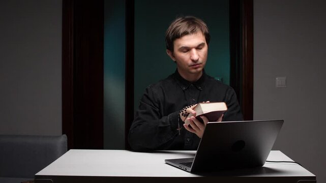Priest giving online sermon from home using laptop and bible