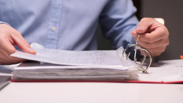 Office worker filing documents in a ring binder at night