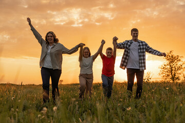 A family joyfully walks together through a green field, celebrating each other's company during a serene sunset ambiance.