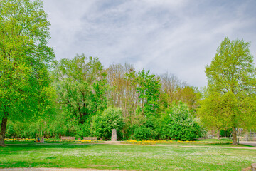Springtime garden in Ingolstadt with trimmed hedges, historic fortress wall and leafy arches in Bavaria.