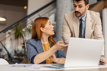 Fototapeta premium Businesswoman sitting at corporate office and explaining her analyzes on laptop to her manager.