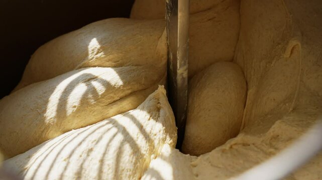 Close-up of dough kneading in a professional bakery mixer the process of bread and pastry making, automated dough preparation equipment in action. High quality 4k footage