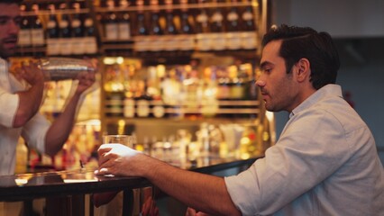 Profile closeup of smiling smart man in white shirt drinking cocktail in Old fashioned of special party beverage vibrant at nightclub on Friday meeting night time at luxurious counter bar. Vinosity.