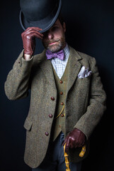 British Gentleman in Tweed Suit and Leather Gloves Doffing Bowler Hat. Vintage Style and Classic Fashion of English Gentleman.