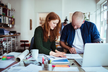 Fototapeta premium Young man and woman working together on a project in a startup company office