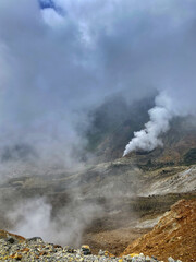 Landscape of volcanic crater area. Seen from a distance in the crater valley the fumarol emit steam gas and covers part of the crater,mount and sky. Papandayan mount,Indonesia,stratovolcano type
