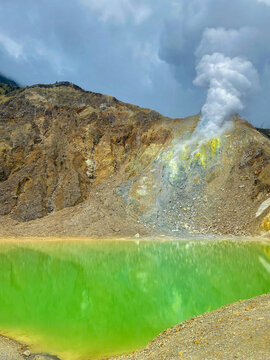 Landscape of fumarol with a yellowish green volcanic lake containing sulfur,Caldera.Fumarol emit thick steam gas,the yellow color in the fumarol area indicates the presence of sulfur content,Solfatara