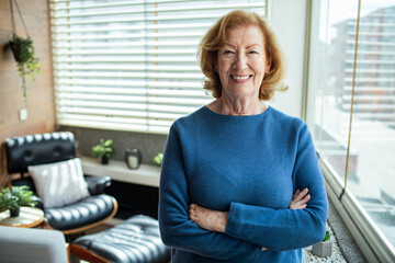 Confident senior woman smiling at home with arms crossed