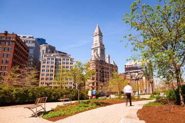 Boston’s vibrant cityscape, blending historic and modern architecture with a bustling downtown, budding trees, and pedestrians in motion, encapsulating the energy of urban life in spring.