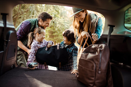 Family packing car trunk together for weekend road trip adventure