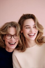 mother and daughter laughing on pastel pink background