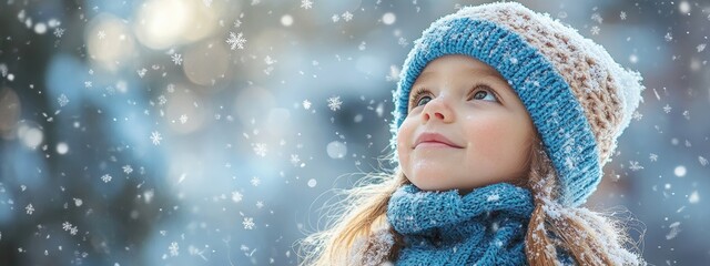 lovely little girl wearing a blue winter hat and scarf, is enjoying snowlakes on a beautiful cold day