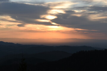 sunset in the black forest mountains under cloudy skies