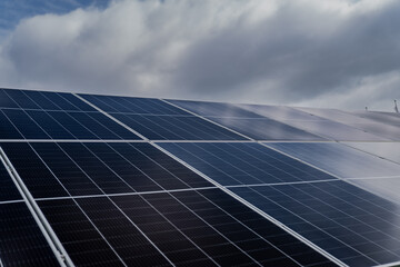 Blue solar panels close up with dark blue and cloudy skies above as sign of changing and...