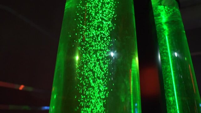 Green liquid and bubbles in slow motion going up a tube of green stuff in neon color