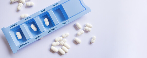 Banner. Plastic pill organizer with tablets sorted by time of day - morning, afternoon, and...