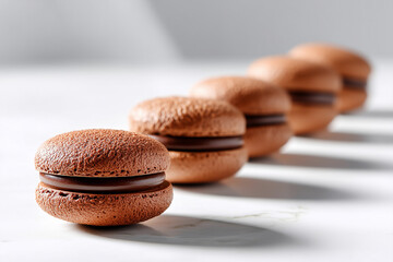 Chocolate sandwich cookies arranged in a line on bright white surface create a minimalistic aesthetic. Clean and simple setting enhances the visual appeal