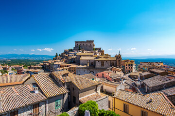 Overlooking the charming rooftops of Soriano nel Cimino in Latium, Italy, with its historic castle and vibrant buildings under a clear blue sky, showcasing the town's rich cultural heritage