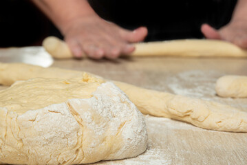 Raw homemade bread, preparing and kneading the bread before baking, on a wooden surface, selective focus.