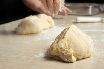 Raw homemade bread, preparing and kneading the bread before baking, on a wooden surface, selective focus.