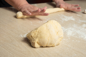 Raw homemade bread, preparing and kneading the bread before baking, on a wooden surface, selective focus.