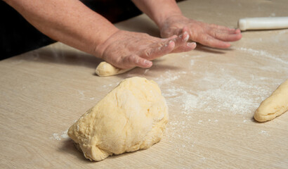 Raw homemade bread, preparing and kneading the bread before baking, on a wooden surface, selective focus.