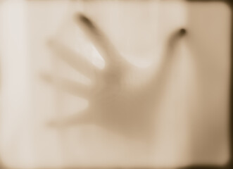 a hand pressed against a translucent sheer cloth surface with diffused lighting. themes of...
