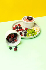 Sweet ice cream yogurt with frozen banana kiwi fruits, blackberry, raspberry berries. Cold fresh summer homemade dessert food on gray plate