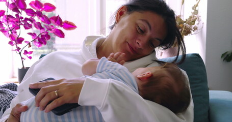Mother smiling warmly at her baby while holding them in her arms, creating a tender and nurturing...