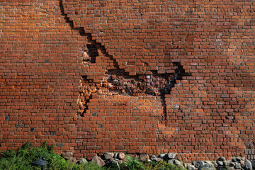 old cracked red brick wall with grass and stone in Warsaw