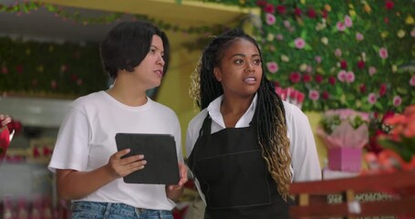 Florists collaborating on tablet inside flower shop, exchanging ideas and reviewing plans for business tasks