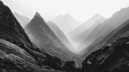 Misty mountain landscape with dramatic peaks in monochrome tones.