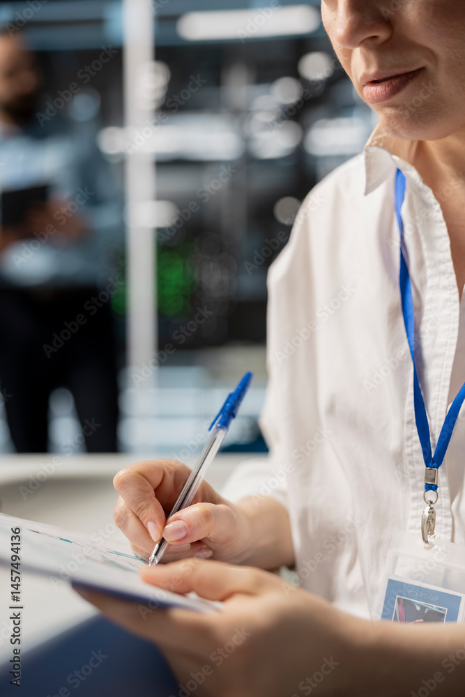 Poster woman in data center taking note on fixes to be made after running diagnostic scripts on computer. s