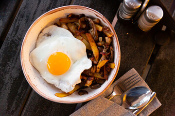Delicious country style lunch of homemade fried potatoes with onion and mushrooms served with sunny side up egg..