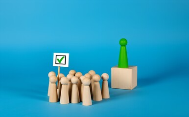 Wooden Figures: A group of wooden figures represent the electorate listening to a green wooden figure on a cube, indicating a concept about power, voting or decisions.