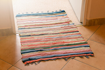 Colorful striped textile rug on tiled floor at open doorway
