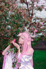 Obraz premium Deer dryad girl against the background of a blooming pink apple tree