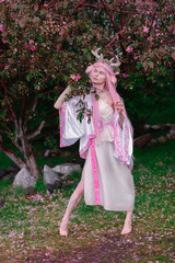 Deer dryad girl against the background of a blooming pink apple tree